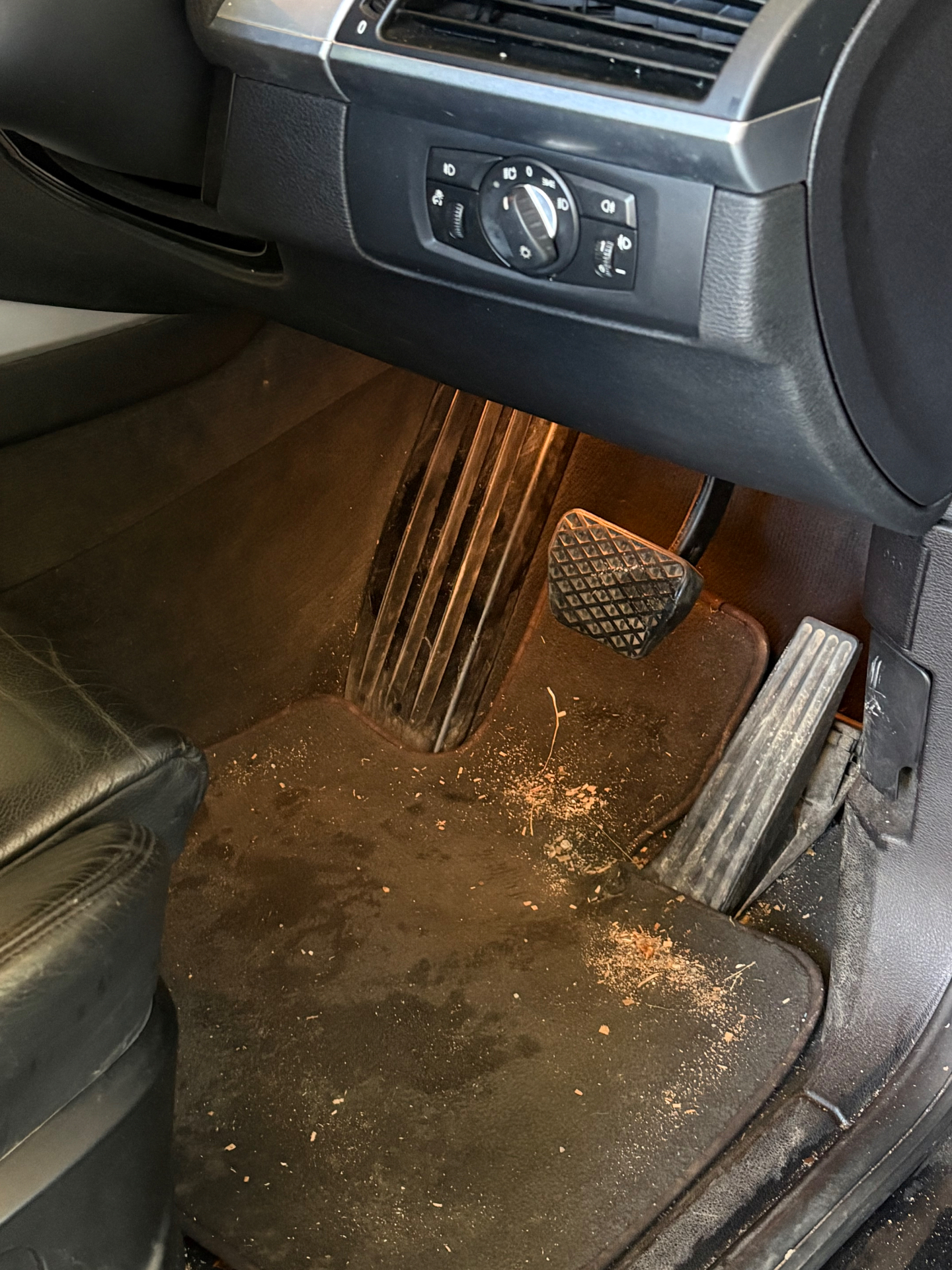 Interior auto înainte de curățare, cu murdărie vizibilă pe covoraș și în zona pedalelor